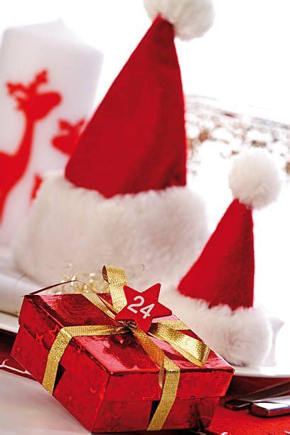 A Santa Hat Sitting On Top Of A Table Next To A Red Box With A Gold Ribbon