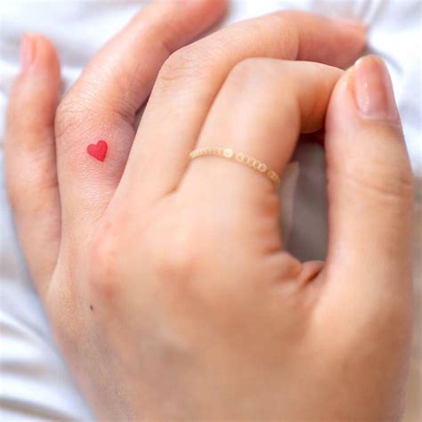 Small Red Heart Tattoo On The Left Ring Finger