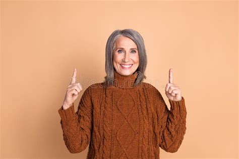 Smiling Mature Woman Gesturing With Raised Fingers In Stylish Casual