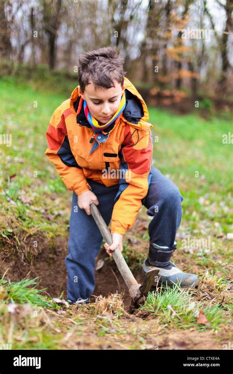 Boy Digging On A Grass Field In The Countryside Stock Photo Alamy