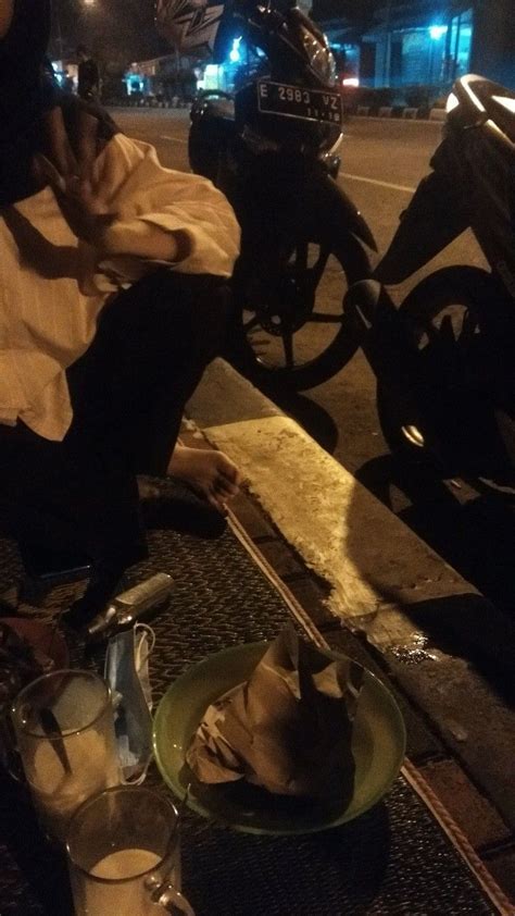 A Man Sitting On The Ground Next To A Motorcycle At Night With His Head