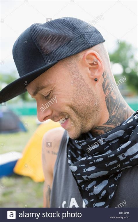 Portrait Smiling Young Man With Neck Tattoo And Baseball Hat Looking