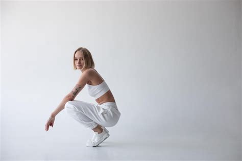 Une Belle Fille Blonde Dans Un Haut Blanc Et Des Collants Posant Sur Un Fond Blanc Photo Gratuite