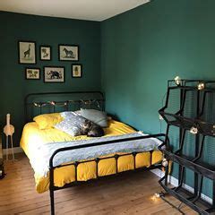 A Bed Room With A Neatly Made Bed Next To A Green Wall And Pictures On