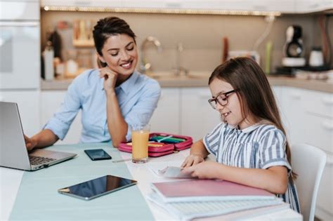 Belle jeune mère aidant sa fille cadette à faire ses devoirs Photo