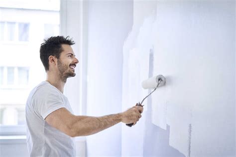 Smiling Man Painting Wall In Apartment Stock Photo