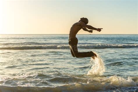 L Homme Sautant Sur La Plage Au Coucher Du Soleil Photo Stock Image