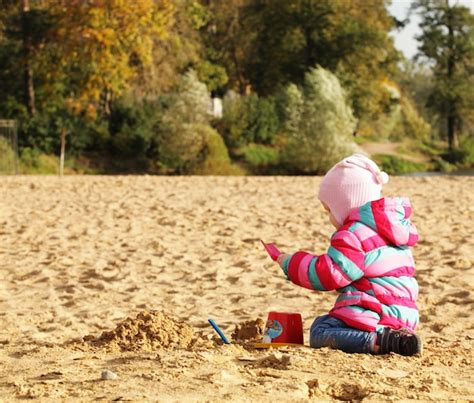 Niña jugando con arena en la playa de otoño Foto Premium