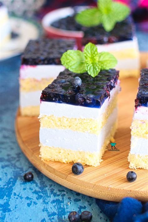 Two Pieces Of Cake With Blueberries And Mint On A Wooden Platter Next