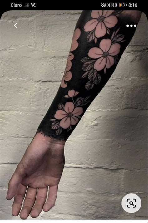 A Person With A Black And Pink Flower Tattoo On Their Arm Holding Onto