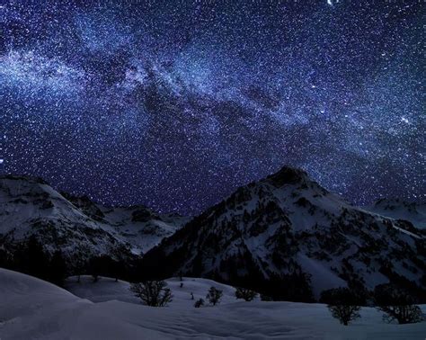 The Night Sky Is Filled With Stars Above Snowy Mountains