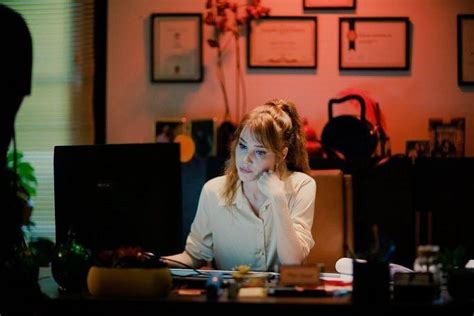 A Woman Sitting At A Desk In Front Of A Computer