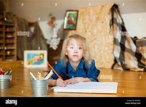 Petite fille blonde allongée sur le sol et le dessin avec des crayons de couleur Photo Stock Alamy