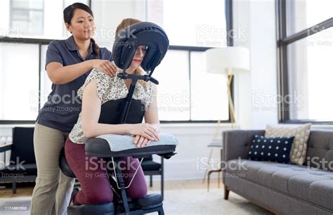 Chinese Woman Massage Therapist Giving A Neck And Back Pressure Treatment To An Attractive Blond