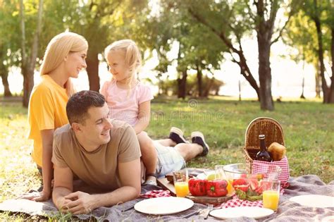 Familia Feliz Que Tiene Comida Campestre En Parque Foto De Archivo