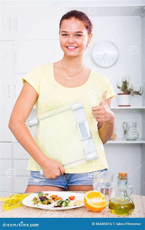 Muchacha Que Se Coloca Con Las Escalas En Cocina Foto De Archivo