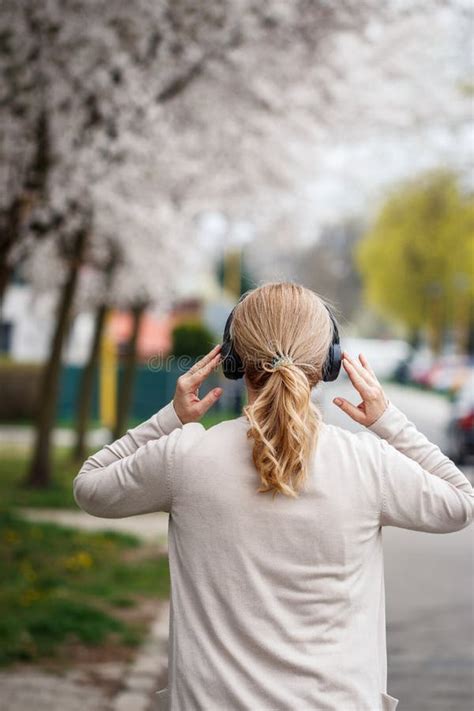 Woman With Wireless Headphones Walking On City Street And Listening