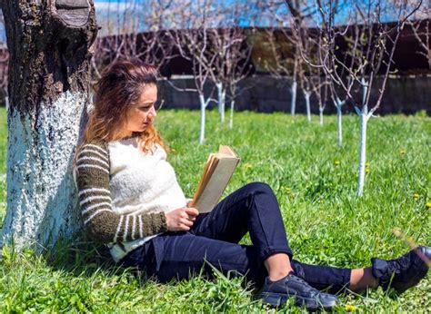 Una Mujer Hermosa Leyendo Un Libro Sentada En El Parque Foto Premium