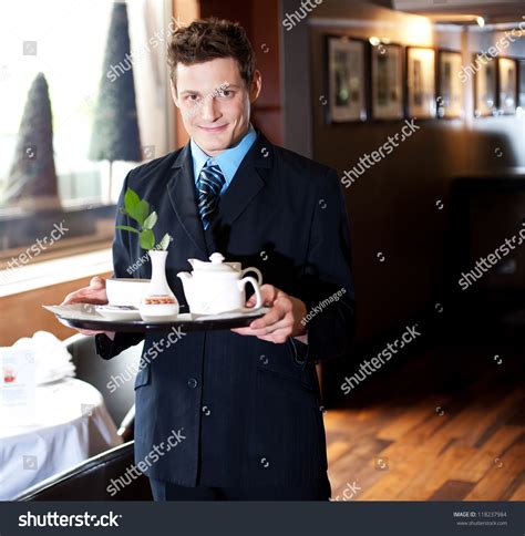 Good Looking Host In A Restaurant Holding Tea Tray For Guests Stock