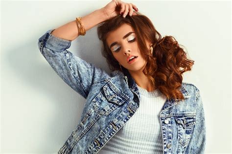 Schöne junge blonde Frau im schönen Kleid und in der Jeansjacke auf weißem Hintergrund in