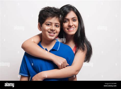 Portrait Of Sister With Arms Around Her Brother Looking At Camera And