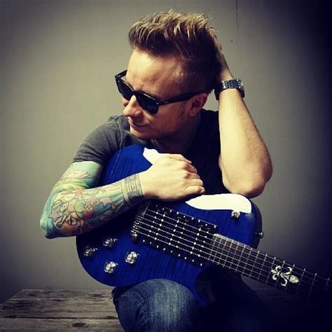 A Man Sitting On The Floor With His Guitar In Front Of Him And Holding