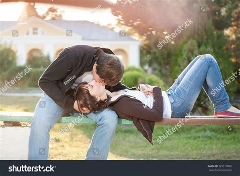 Happy Couple Against The Background Of Park Kissing Sitting On The Park