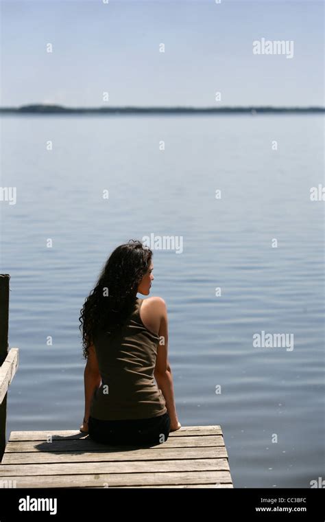 Brunette Sat At The End Of Jetty Stock Photo Alamy