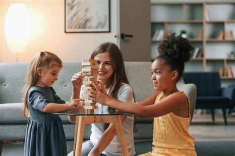 Premium Photo A Young Woman With Two Girls Is Playing A Wooden Tower Game Indoors Together