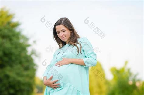 怀孕的女孩紧抱她怀孕的肚子幸福的怀孕的女 包图企业站