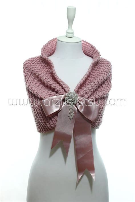 A White Mannequin Wearing A Pink Knitted Scarf With A Bow On It