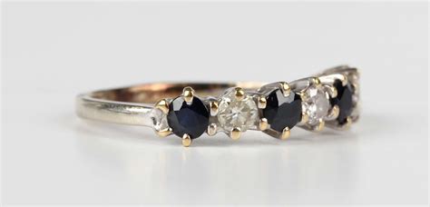 A Sapphire And Diamond Seven Stone Half Hoop Ring Claw Set With Three