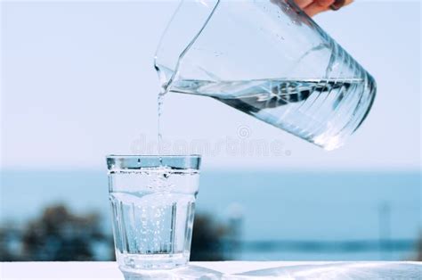 El Agua Pura De Un Jarro Se Vierte En Un Cubilete De Cristal Vidrio Con