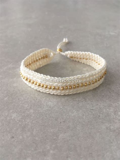 Two White And Gold Beaded Bracelets Sitting On Top Of A Gray Surface