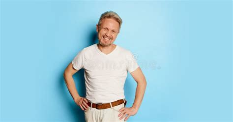 Portrait Of Mature Man In White T Shirt Posing Isolated Over Blue Studio Background Looks Happy