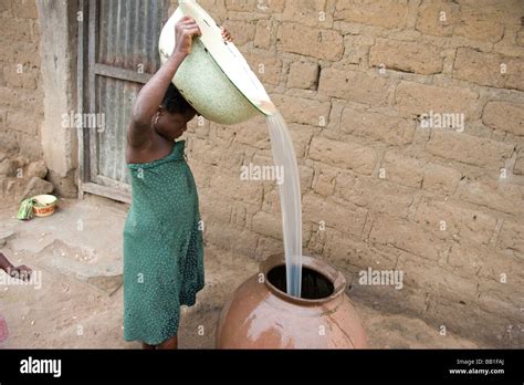 Woman Pouring Water From Large Bowl On Her Head Into Container Village