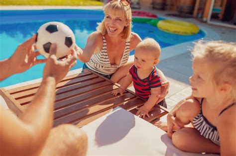 Madre Y Padre Jugando Con Sus Hijos Junto A La Piscina Durante Las