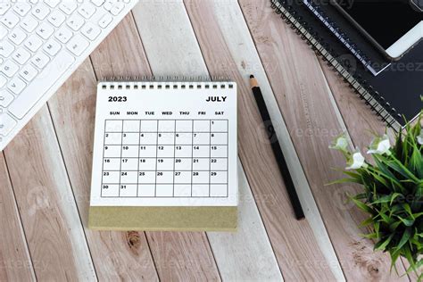 White July 2023 Desk Calendar On Wooden Desk Directly Above Flat Lay