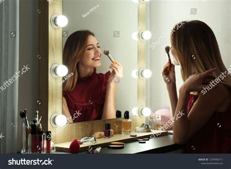 Woman Putting On Makeup In Mirror