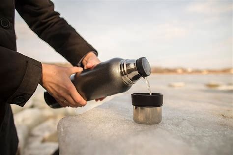 El Hombre Vierte T Caliente Del Termo En La Taza Que Se Encuentra En