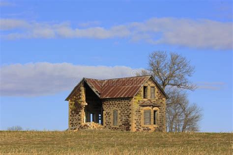 Abandoned Kansas Limestone House In A Farm Field With A Tree And Blue