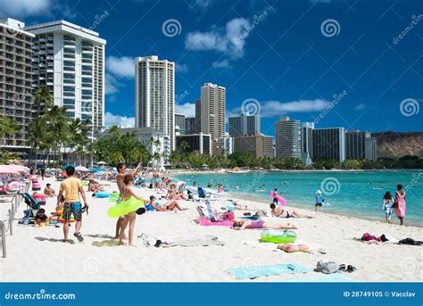 Tourist Sunbathing And Surfing On The Waikiki Beach In Hawaii