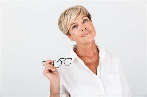 Retrato de mujer adulta rubia sosteniendo anteojos y mirando a cámara