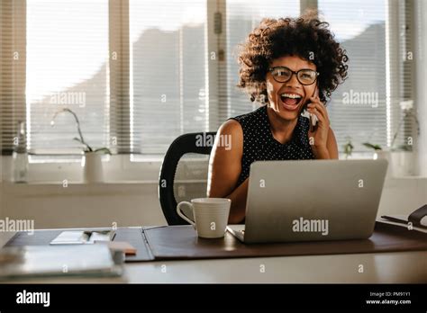 Portrait Of Laughing Young Woman Sitting At Her Desk In Office African