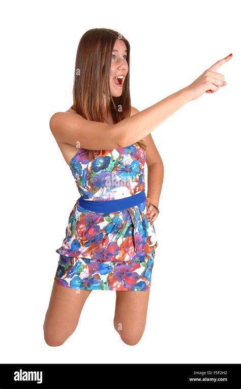 A Pretty Teenage Girl Kneeling On The Floor In A Colorful Dress And Pointing With Her Finger