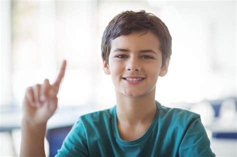 Retrato De Estudante Feliz Levantando A Mão Na Sala De Aula Foto Premium