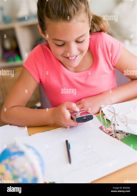 Young Girl Distracted From Her Homework Playing With A Cellphone Stock