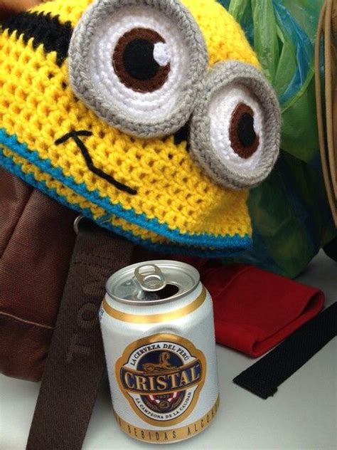 There Is A Crocheted Hat With Eyes On It And A Can Of Beer Next To It