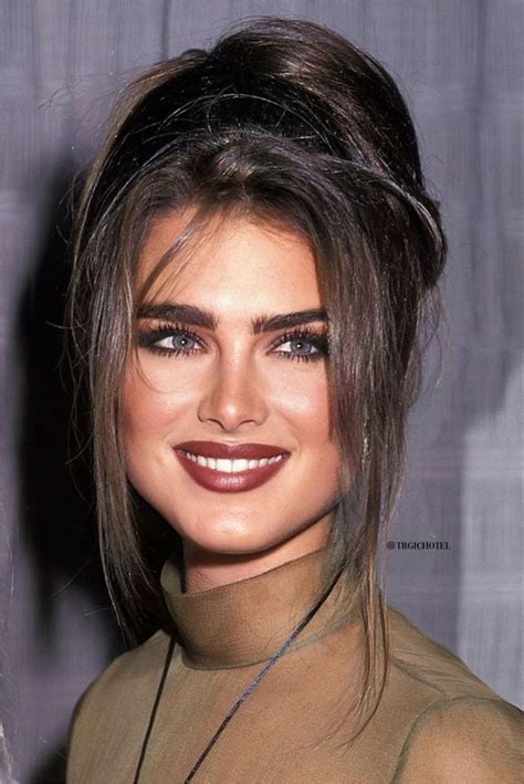 A Close Up Of A Person Wearing A Brown Shirt And Smiling At The Camera