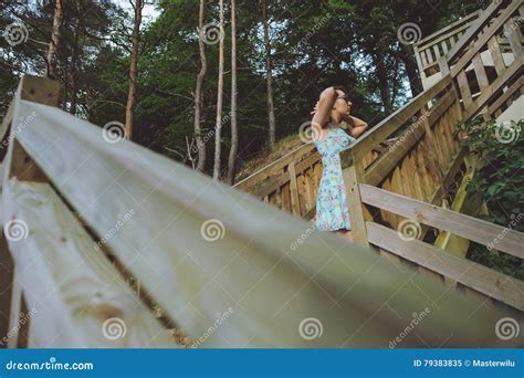 Menina Que Senta Se Nas Escadas De Madeira No Parque E No Sorriso